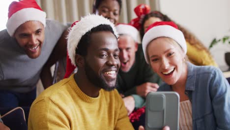 Fröhliche-Gruppe-Verschiedener-Freunde,-Die-Ihr-Smartphone-Für-Videoanrufe-Auf-Der-Weihnachtsfeier-Nutzen