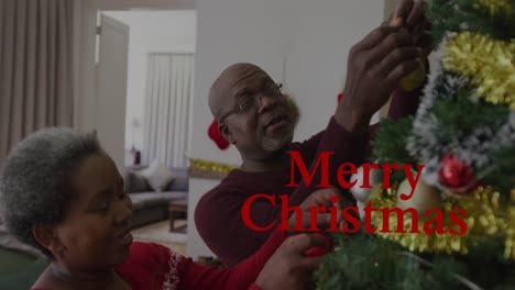 Animation-of-christmas-greetings-text-over-african-american-couple-decorating-christmas-tree