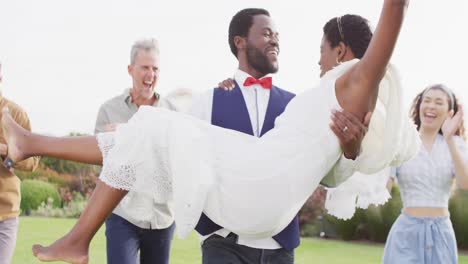 Happy-african-american-couple-carrying-and-walking-during-wedding