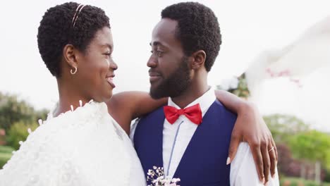 Happy-african-american-couple-embracing-and-smiling-during-wedding