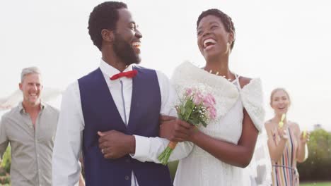 Happy-african-american-couple-holding-hands-and-walking-during-wedding