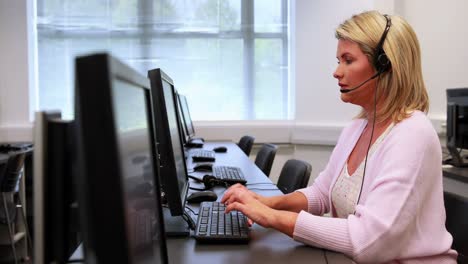 Woman-typing-at-computer-while-speaking-with-headset