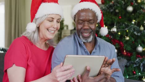 Happy-senior-diverse-couple-using-tablet-at-christmas