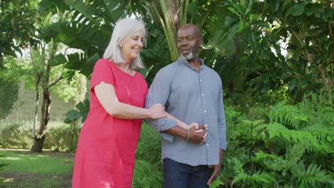 Happy-senior-diverse-couple-walking-in-garden