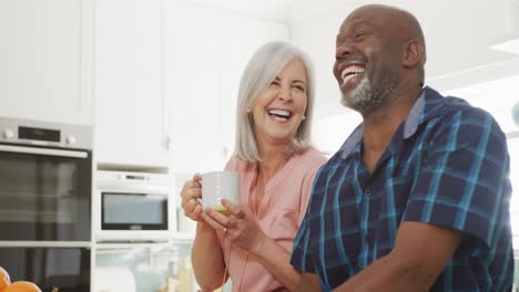 Glückliches-älteres,-Vielfältiges-Paar,-Das-Im-Wohnzimmer-Sitzt-Und-Kaffee-Trinkt