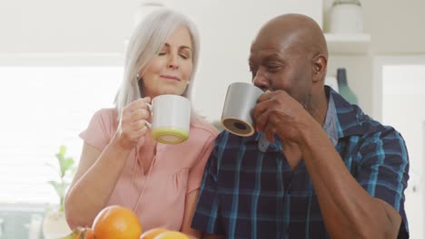 Glückliches-älteres,-Vielfältiges-Paar,-Das-Im-Wohnzimmer-Sitzt-Und-Kaffee-Trinkt