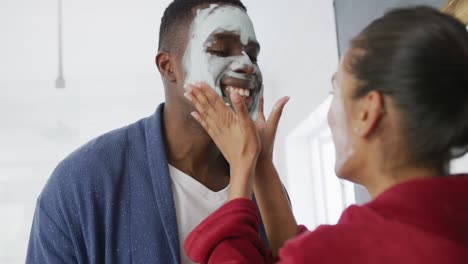 Happy-diverse-couple-doing-masks-in-bathroom-and-working-in-garden