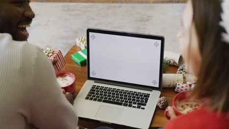 Video-of-happy-diverse-couple-making-christmas-laptop-video-call-at-home,-copy-space-on-screen