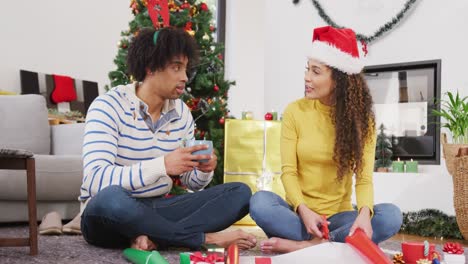 Video-Eines-Glücklichen,-Vielfältigen-Paares-Mit-Weihnachtsgeweih-Und-Weihnachtsmütze,-Das-Sich-Zu-Hause-Unterhält