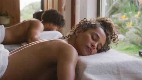 Video-of-relaxed-diverse-couple-lying-with-eyes-closed-on-massage-tables-at-health-spa