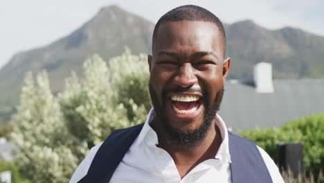 Video-portrait-of-happy-african-american-groom-laughing-to-camera-at-outdoor-wedding