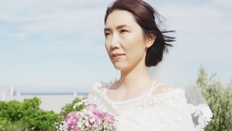 Video-Einer-Glücklichen-Asiatischen-Braut,-Die-Bei-Einer-Hochzeit-Im-Freien-Mit-Einem-Blumenstrauß-Spazieren-Geht-Und-Lächelt