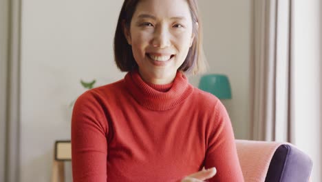 Video-portrait-of-happy-asian-woman-smiling-to-camera-at-home
