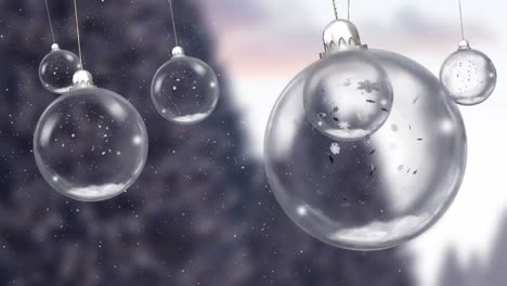 Animation-of-christmas-baubles-dangling-over-snow-falling-in-winter-scenery