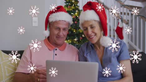 Animation-of-snowflakes-over-senior-caucasian-couple-wearing-santa-hats-and-using-tablet
