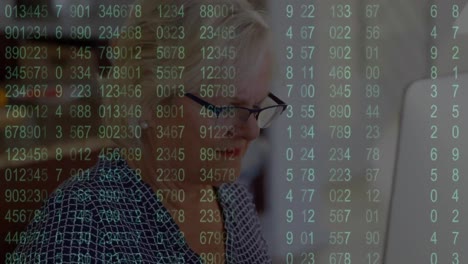 Animation-of-increasing-numbers-over-senior-caucasian-woman-working-on-desktop