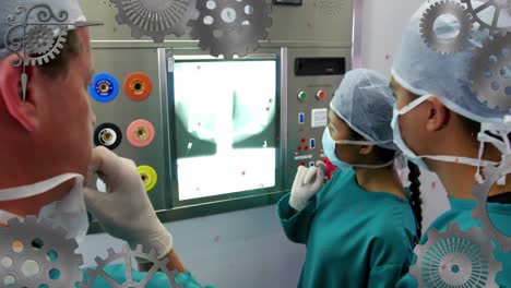 Animation-of-cogs-moving-over-diverse-surgeons-in-hospital