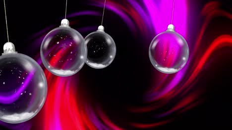 Animation-of-christmas-baubles-dangling,-snow-falling-with-glowing-light-trails-on-black-background