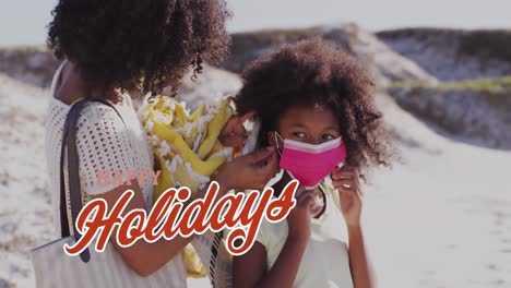 Animation-of-happy-holidays-text-over-african-american-woman-and-her-daughter-at-beach