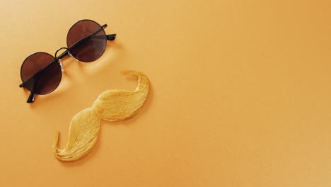 Video-of-blonde-false-moustache-and-round-sunglasses-on-yellow-background-with-copy-space