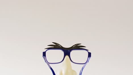 Video-Von-Befestigten-Plastikaugenbrauen,-Brillen,-Nase-Und-Schnurrbart-Auf-Weißem-Hintergrund-Mit-Kopierraum