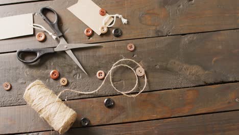 Video-of-scissors,-twine-string,-buttons-and-gift-tags-on-dark-wood-boards-with-copy-space