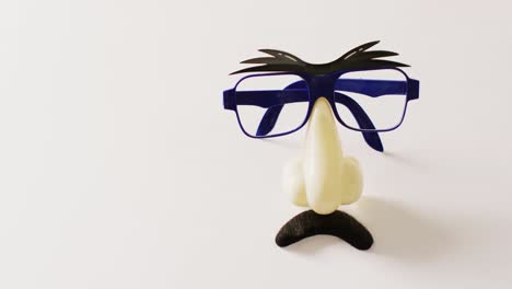 Video-of-attached-plastic-eyebrows,-glasses,-nose-and-moustache-on-white-background-with-copy-space