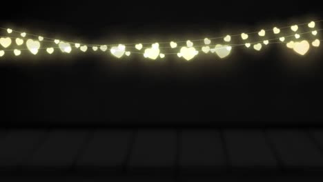 Animation-of-yellow-heart-shaped-glowing-fairy-lights-hanging-against-copy-space-on-black-background