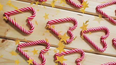 Animation-of-stars-over-candy-canes-on-wooden-backrgound