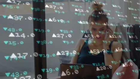 Animation-of-stock-market-data-processing-over-caucasian-woman-with-laptop-talking-on-smartphone