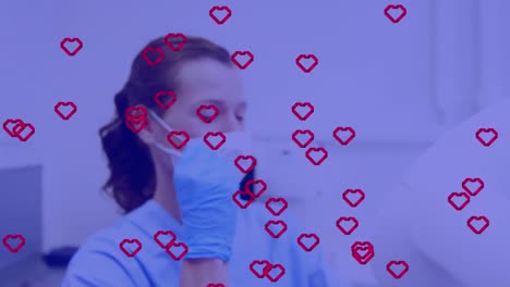 Animation-of-red-hearts-and-purple-tint-over-female-dentist-in-face-mask