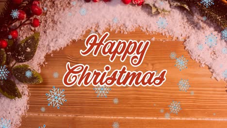 Animation-of-happy-christmas-text-banner-and-snowflakes-over-christmas-decorations-on-wooden-surface
