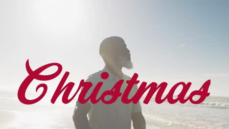 Animation-of-christmas-greetings-text-over-senior-african-american-man-on-beach