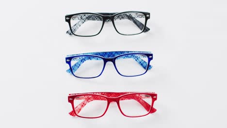 Video-of-three-coloured-pairs-of-glasses-on-white-background-with-copy-space