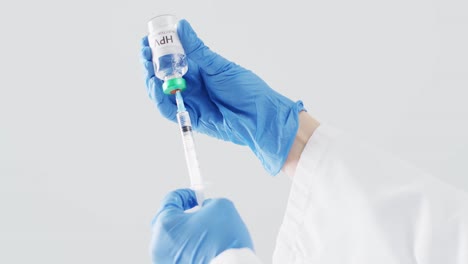 Video-Der-Hände-Eines-Arztes-In-OP-Handschuhen,-Der-Die-Spritze-Mit-HPV-Impfstoff-Füllt,-Mit-Grauem-Kopierraum
