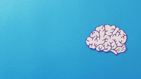 Video-of-white-and-purple-paper-brain-on-blue-background-with-copy-space