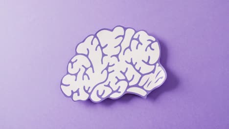 Video-of-purple-and-white-paper-brain-on-purple-background-with-copy-space