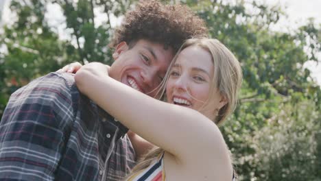 Portrait-of-happy-diverse-couple-embracing-in-garden-on-sunny-day