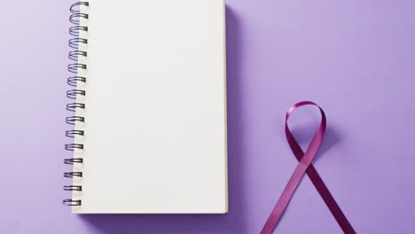 Video-of-purple-add-or-adhd-awareness-ribbon-and-notebook-with-copy-space,-on-purple-background