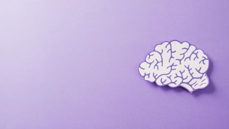 Video-of-purple-and-white-paper-brain-on-purple-background-with-copy-space