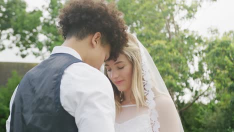 Happy-diverse-couple-in-garden-on-sunny-day-at-wedding