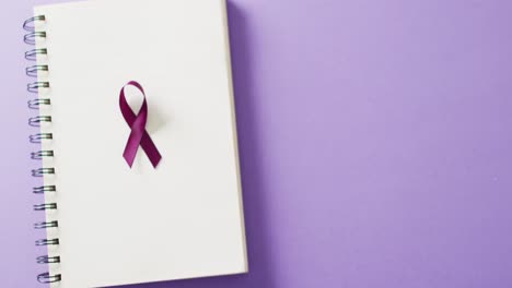 Video-of-purple-add-or-adhd-awareness-ribbon-on-notebook,-on-purple-background-with-copy-space