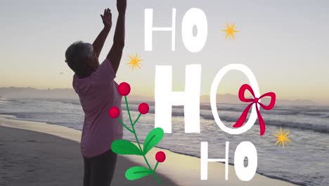 Animation-of-christmas-greetings-text-over-biracial-senior-woman-on-beach