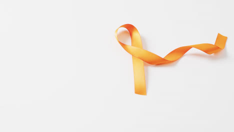 Video-of-orange-multiple-sclerosis-awareness-ribbon-on-white-background-with-copy-space