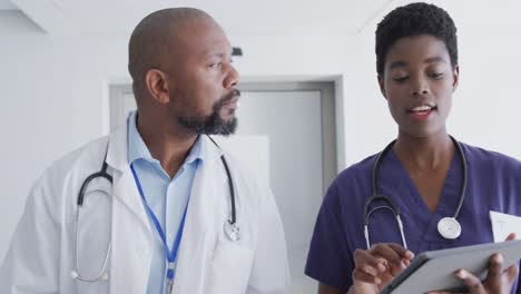 Afroamerikanische-Ärzte-Und-Ärztinnen-Nutzen-Tablet-Und-Sprechen-Im-Krankenhaus