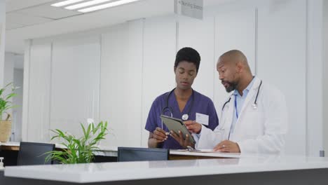 Médicos-Afroamericanos,-Hombres-Y-Mujeres,-Usando-Tabletas,-Hablando-En-El-Hospital