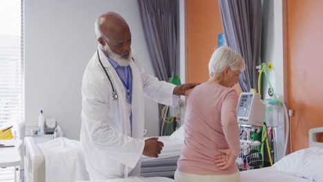 African-american-male-doctor-examining-the-back-of-senior-caucasian-female-patient-at-hospital