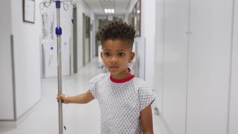Afroamerikanischer-Junge,-Der-Im-Krankenhausflur-Läuft-Und-Einen-Tropfständer-Hält