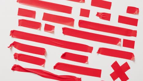 Video-of-close-up-of-multiple-red-tapes-pieces-on-white-background