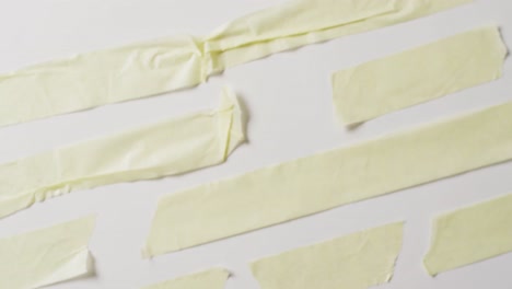 Video-of-close-up-of-multiple-torn-piece-of-yellow-paper-with-copy-space-on-white-background